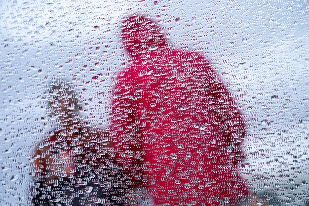 Reflet de deux personnes dans un miroir avec des gouttes de pluie dans la rue jour de pluie en hiver