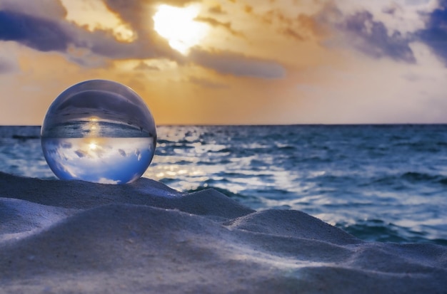 Reflet du ciel et de l'océan sur une boule de cristal sur le sable