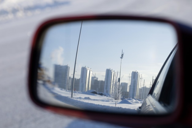 Reflet du paysage urbain dans le rétroviseur de la voiture par une journée d'hiver glaciale