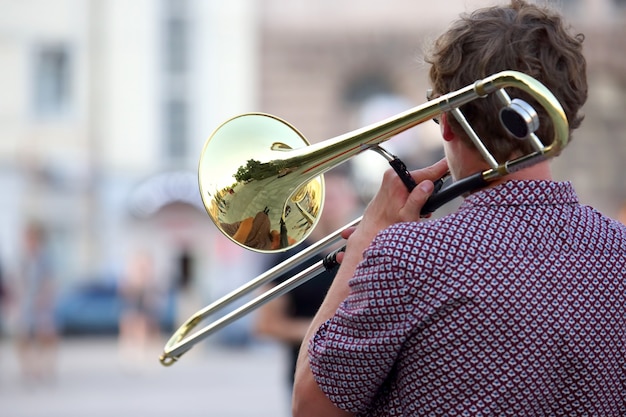 Photo reflet de la rue dans l'instrument trompette solo. un musicien masculin joue du trombone