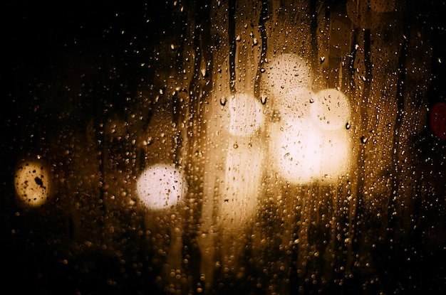 Sur les reflets ronds en verre de la lumière floue des phares de voiture pendant la pluie