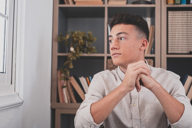 Réflexif caucasien regardant l'écran d'un ordinateur portable, réfléchissant au travail, homme d'affaires indépendant travaillant dans un projet difficile. Adolescent mâle se préparant à la maison dans le bureau à l'intérieur.