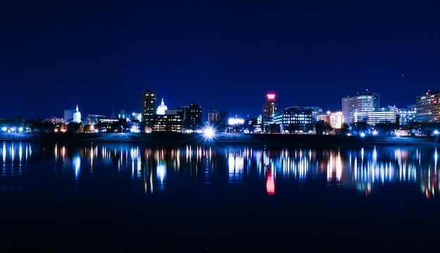 Réflexion de bâtiments éclairés dans la rivière contre le ciel la nuit