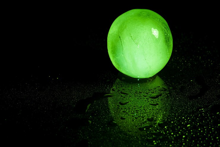 Photo réflexion de boule de glace verte sur fond noir.