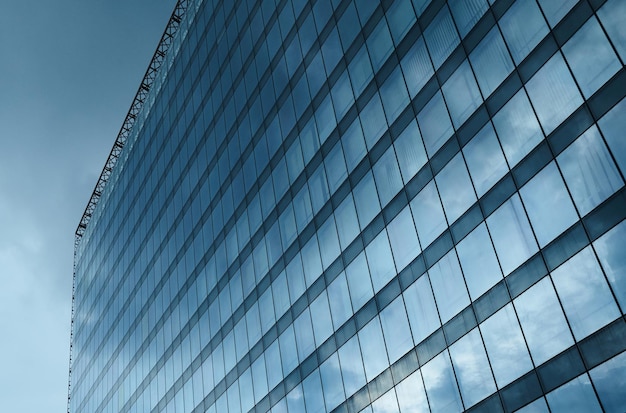 Réflexion de ciel nuageux sur une façade en verre élevée de bâtiment