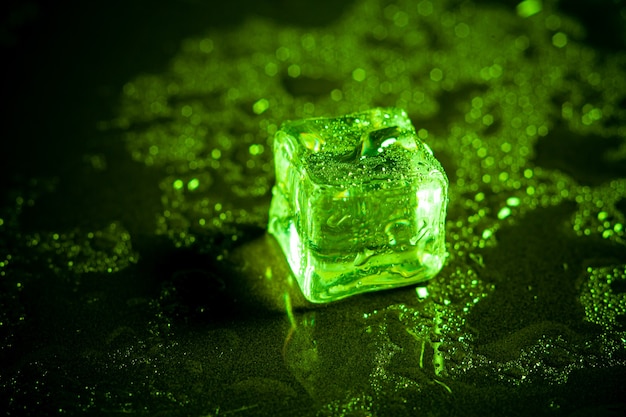 Réflexion de cubes de glace verte sur fond de tableau noir.