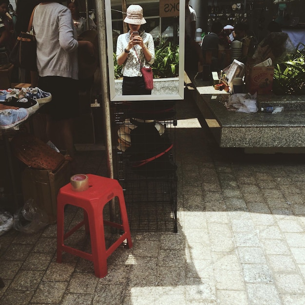 Photo réflexion d'une femme photographiant avec un smartphone dans la rue