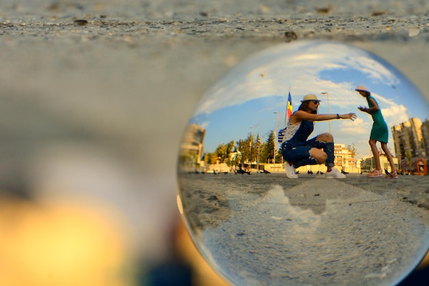 Photo réflexion d'une femme avec sa fille sur une boule de cristal dans la rue