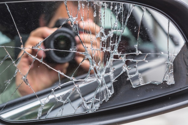 Photo réflexion d'un homme photographiant à travers une caméra sur un miroir latéral cassé