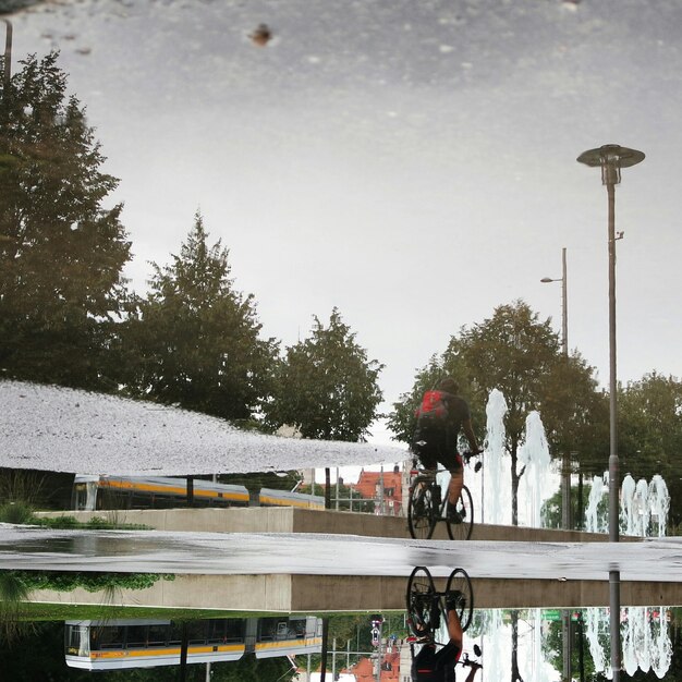 Réflexion d'un homme à vélo dans une flaque d'eau dans la rue