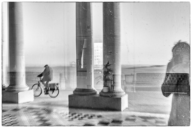 Photo réflexion d'un homme à vélo par des colonnes sur du verre