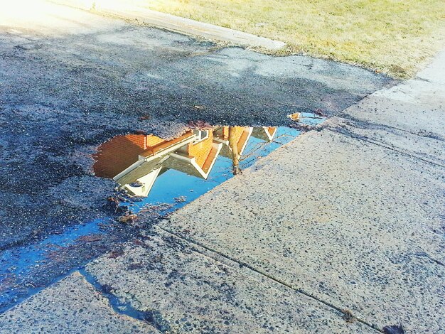 Réflexion d'une maison dans une flaque d'eau sur la route