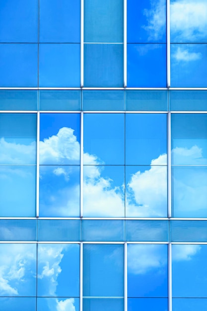 Réflexion de nuages et de ciel bleu sur la surface du mur de bâtiment moderne en verre dans un cadre vertical