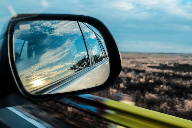 Photo réflexion de la voiture sur le miroir latéral contre le ciel