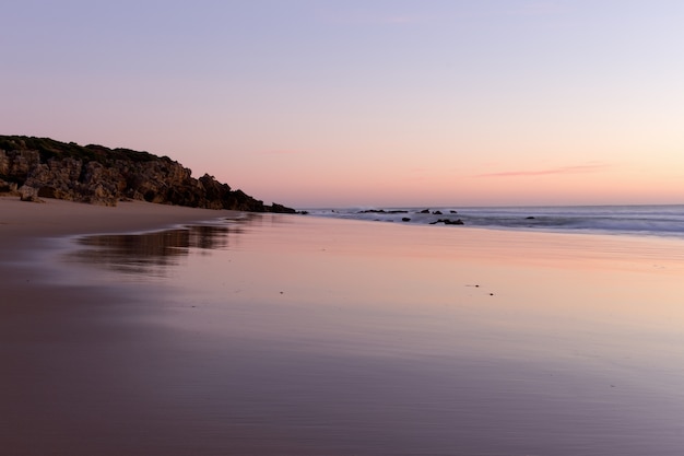 Photo réflexions sur la rive de la plage à la tombée de la nuit