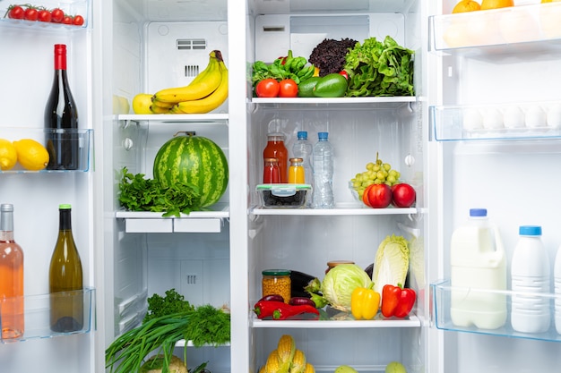 Réfrigérateur ouvert plein de fruits, légumes et boissons