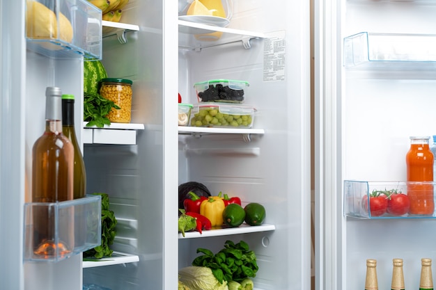 Réfrigérateur ouvert plein de fruits, légumes et boissons