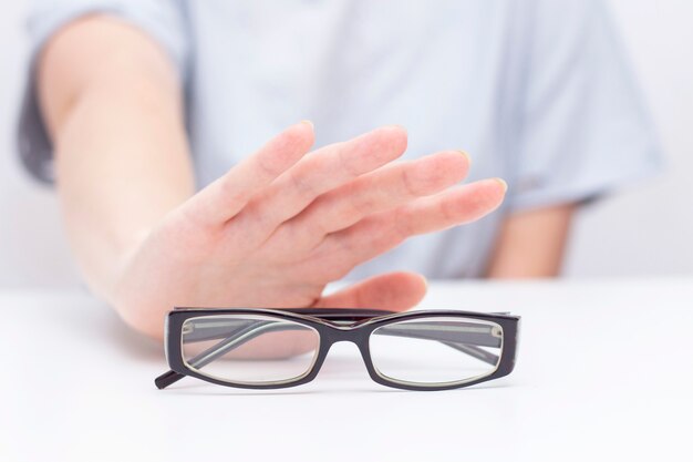 Refus de lunettes pour la vue. les mains refusent les lunettes. croix sur des verres. Amélioration de la vision, correction de la vision au laser.