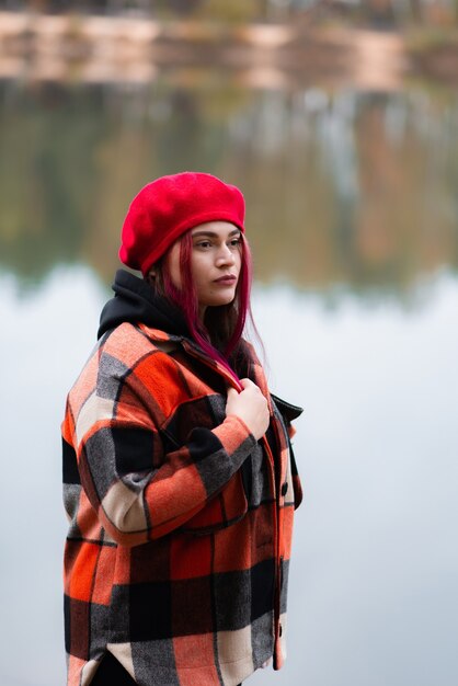 Regard réfléchi d'une fille dans un manteau à carreaux rouge sur un fond de lac