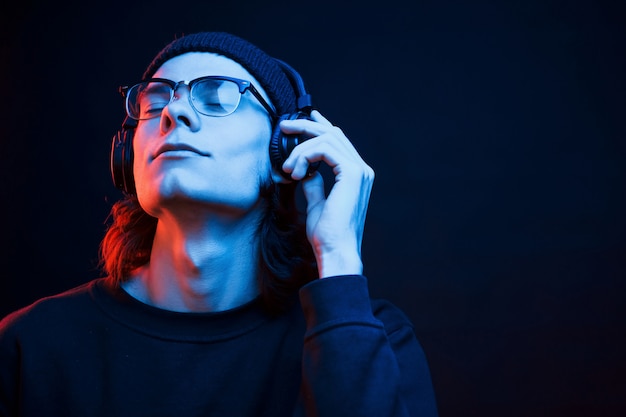 Regard rêveur. Studio tourné en studio sombre avec néon. Portrait d'homme sérieux