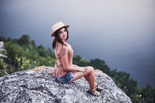 Regard satisfait. Jolie fille touristique posant au bord de la montagne avec un lac d'eau claire en arrière-plan.