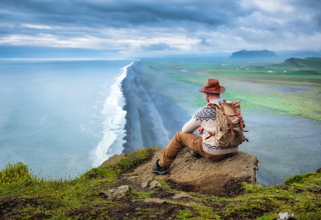 Regard de voyageur sur le bord de mer depuis le rocher Concept de voyage et de vie active Aventure et voyage en Islande