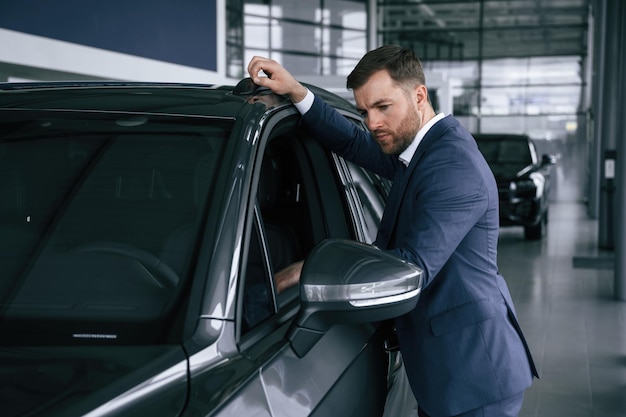 Regardant l'automobile Un homme d'affaires est dans un concessionnaire de voitures