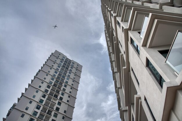 regardant le bâtiment urbain de grande hauteur avec un avion survolant