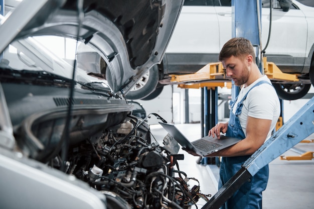 En regardant le prix des articles. Employé dans l'uniforme de couleur bleue travaille dans le salon automobile