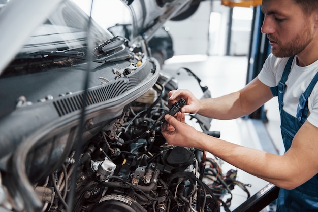 Regardant ce qu'il y a à l'intérieur. Employé dans l'uniforme de couleur bleue travaille dans le salon automobile