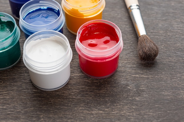 Regardant vers le bas sur trois pots de peinture ouverts de peinture colorée se tenait sur un plancher en bois de style minable