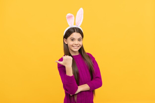 Regarde là-bas. enfance heureuse. enfant lapin. joyeuses fêtes de pâques. enfant drôle dans le doigt pointé de l'oreille de lièvre. adolescente porte un costume de lapin. chasse au lapin de Pâques. publicité. Prêt pour la fête.