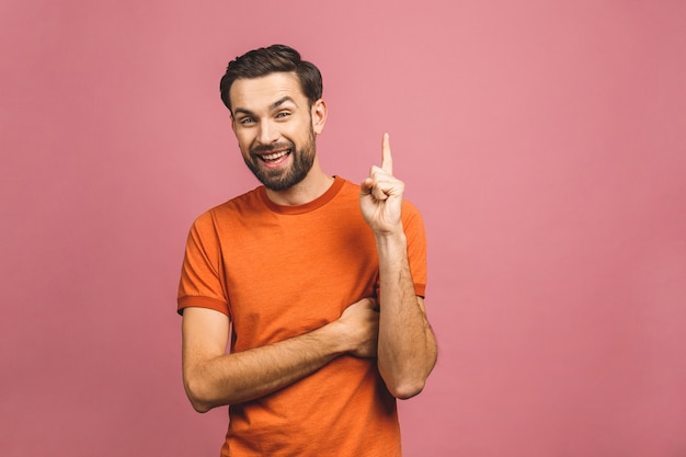 Regarde là-bas! Heureux jeune bel homme décontracté pointant loin et souriant en position debout.