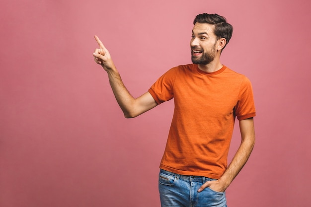 Regarde là-bas! Heureux jeune bel homme décontracté pointant loin et souriant en position debout.