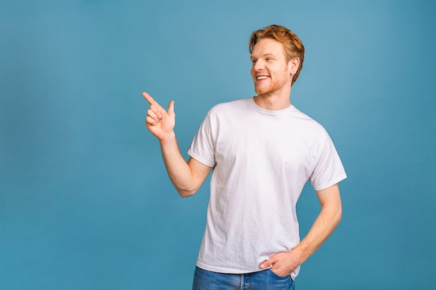 regarde là-bas! heureux jeune bel homme décontracté pointant vers l'extérieur et souriant