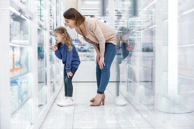 Regarde maman. Réfléchi positif femme et fille debout et regardant la vitrine