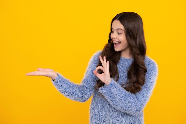 Regarder l'annonce L'enfant adolescent pointe de côté montre un espace de copie vierge pour la présentation de l'idée de promotion de texte pose sur fond jaune Heureux adolescent émotions positives et souriantes d'une adolescente