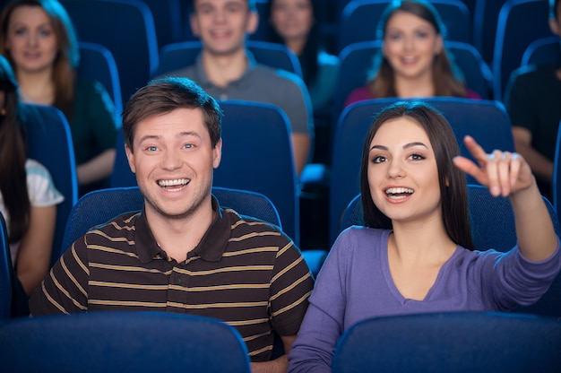 Regarder un film ensemble. Heureux jeune couple mangeant du pop-corn et buvant du soda en regardant un film au cinéma