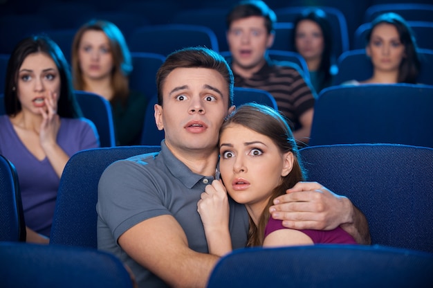 Regarder un film d'horreur. Jeune couple choqué se liant en regardant un film au cinéma