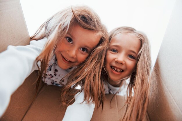 Regarder à l'intérieur d'une boîte en papier Deux jolies petites filles à l'intérieur à la maison ensemble Enfants s'amusant