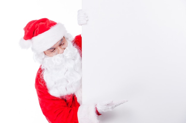 Regardez ça. Le Père Noël traditionnel pointant l'espace de copie en se tenant debout sur fond blanc