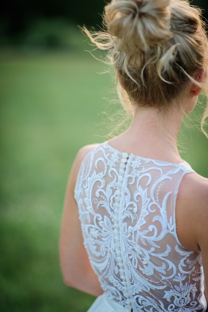 Regardez par derrière à la mariée avec le cou tendre et le dos avec des lacets