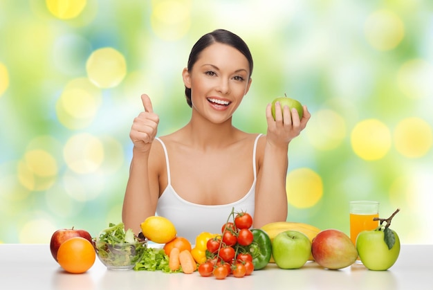 régime alimentaire, alimentation saine, nourriture et concept de personnes - belle femme avec des fruits et légumes montrant les pouces vers le haut sur le fond des lumières vertes d'été
