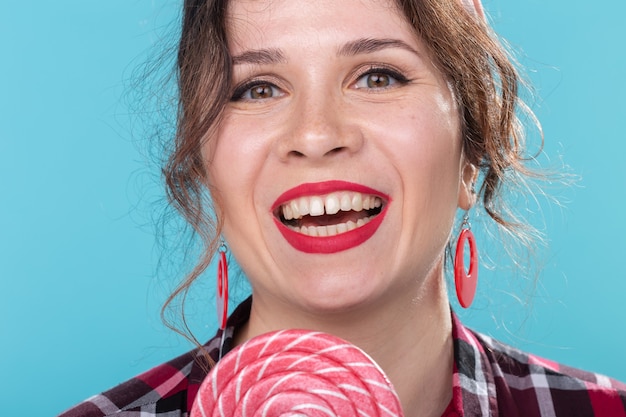 Régime alimentaire, dessert et malbouffe - style pin-up femme close-up avec sucette sur fond bleu