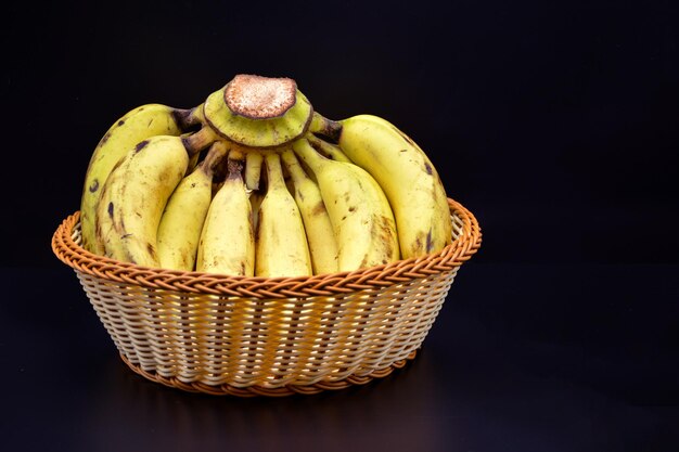 Photo régime de bananes dans le panier isolé sur fond noir