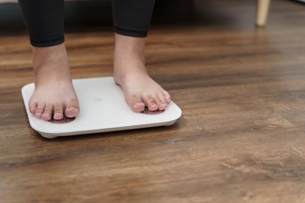 Régime gras et pieds d'échelle debout sur des balances électroniques pour le contrôle du poids Instrument de mesure en kilogramme pour un contrôle de l'alimentation