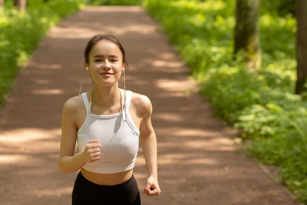 Régime sportif mode de vie sain Une fille au casque court dans le parc en souriant