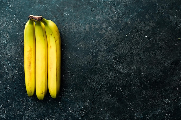 Régimes tropicaux de bananes jaunes sur fond de pierre noire Vue de dessus