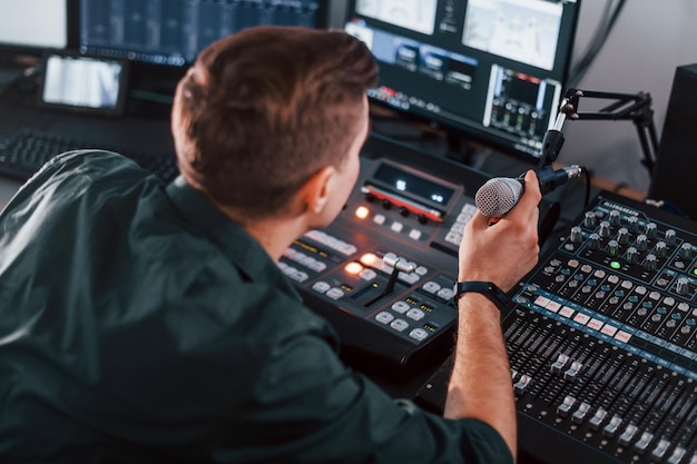 Réglage de l'équipement Le jeune homme est à l'intérieur dans le studio de radio est occupé par la diffusion