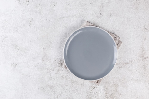 Réglage de la table avec assiette grise vide et serviette en lin